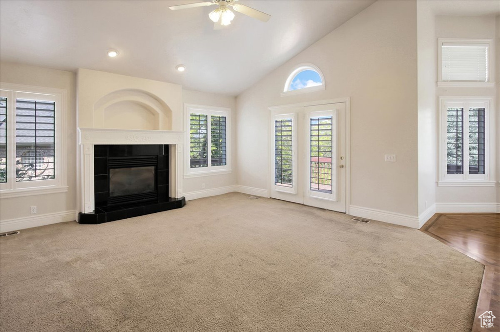 Unfurnished living room with plenty of natural light, ceiling fan, carpet flooring, high vaulted ceiling, and recessed lighting