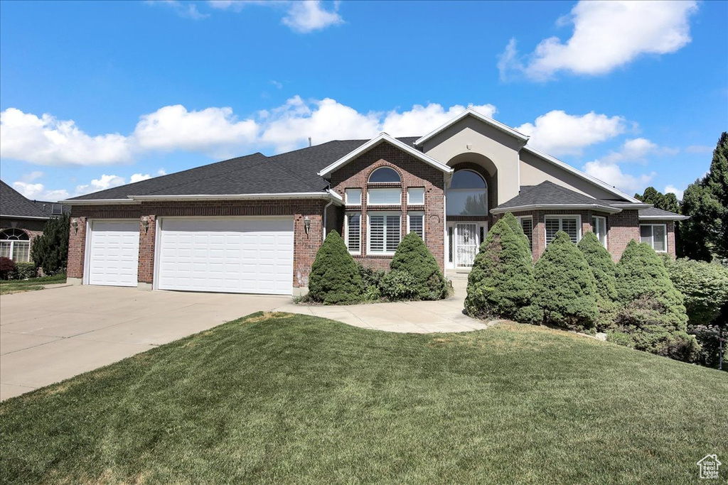 View of front of property with concrete driveway, a garage, a front yard, and brick siding