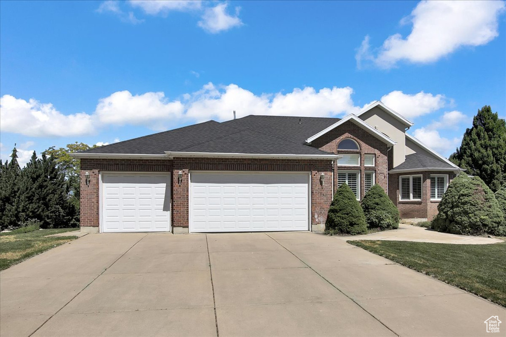 View of front of house featuring concrete driveway, brick siding, and an attached garage
