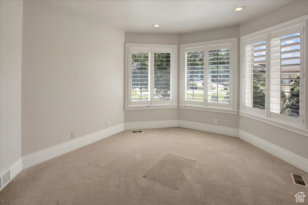 Empty room with light carpet and recessed lighting