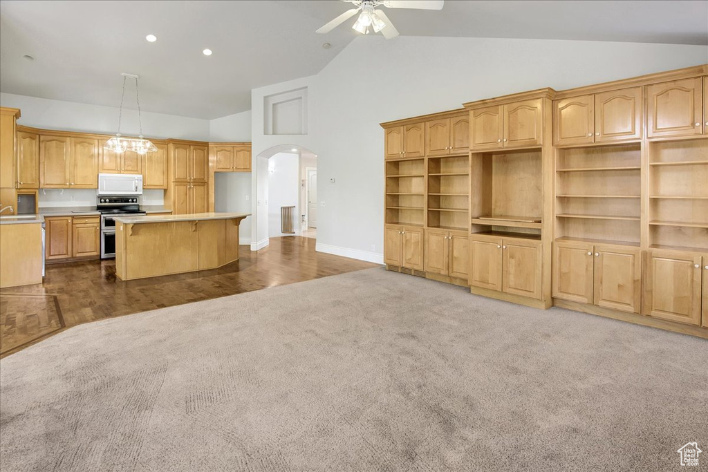 Kitchen featuring white microwave, range with two ovens, dark carpet, arched walkways, and a center island