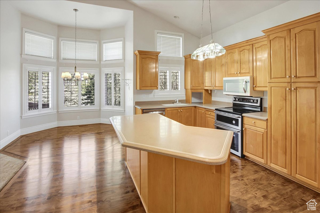 Kitchen with double oven range, a chandelier, white microwave, high vaulted ceiling, and light countertops