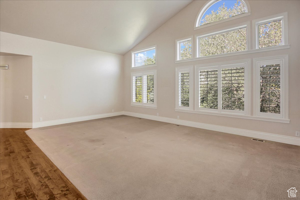 Unfurnished living room featuring high vaulted ceiling and wood finished floors