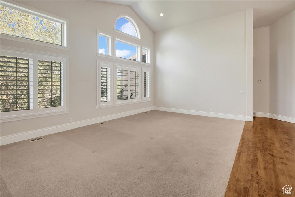 Spare room with high vaulted ceiling and carpet flooring