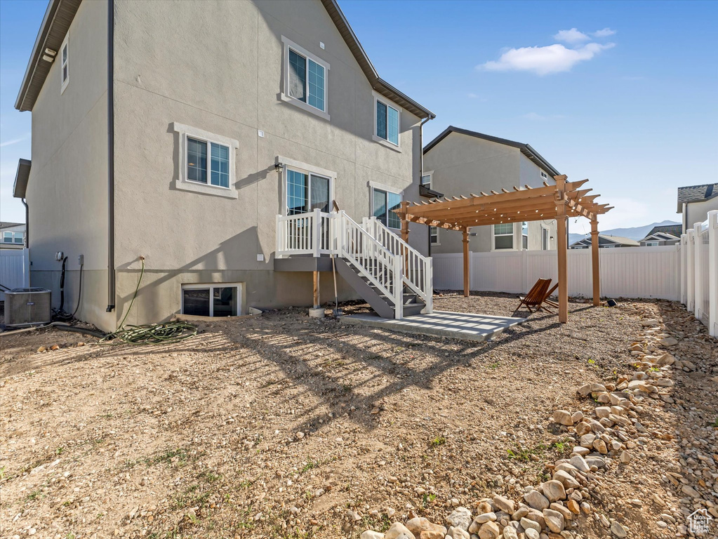 Rear view of property with stucco siding, a fenced backyard, a pergola, and a patio