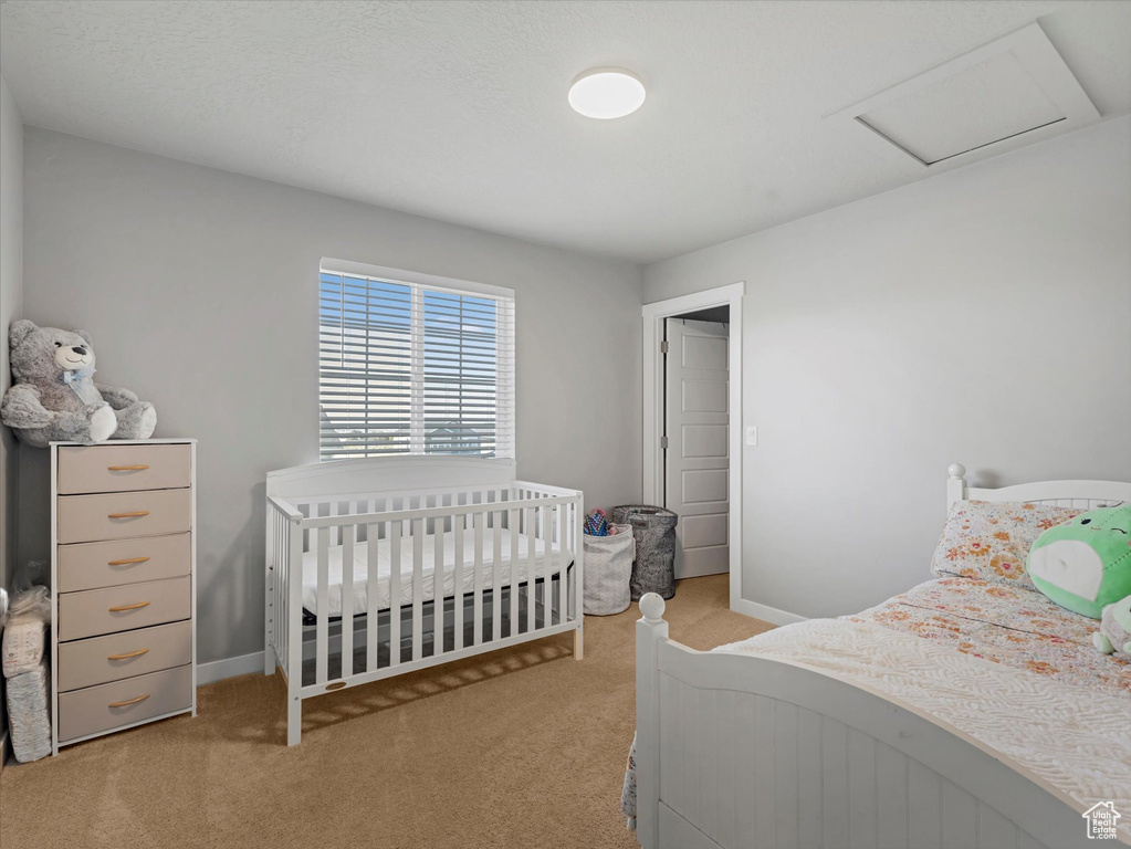 Carpeted bedroom featuring attic access and baseboards