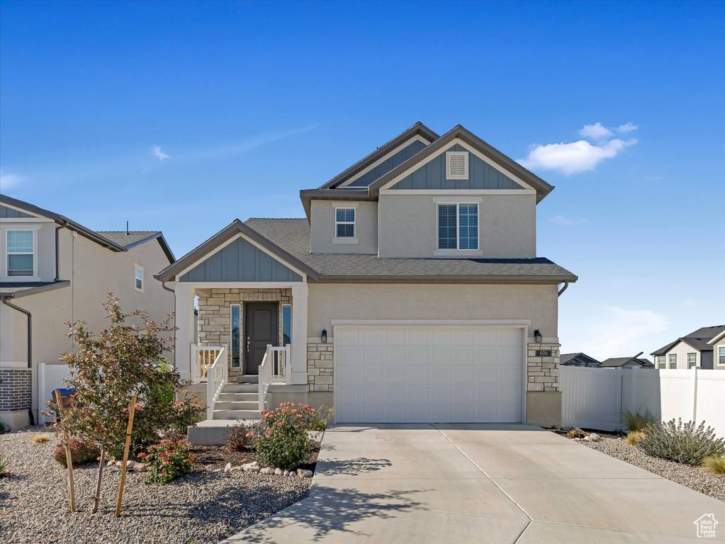 View of front of property featuring stone siding, concrete driveway, a garage, and stucco siding