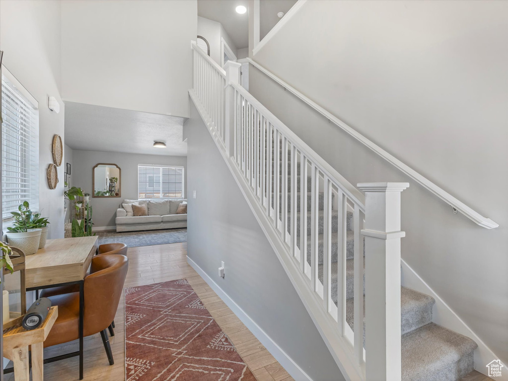 Stairway featuring wood finished floors and a towering ceiling