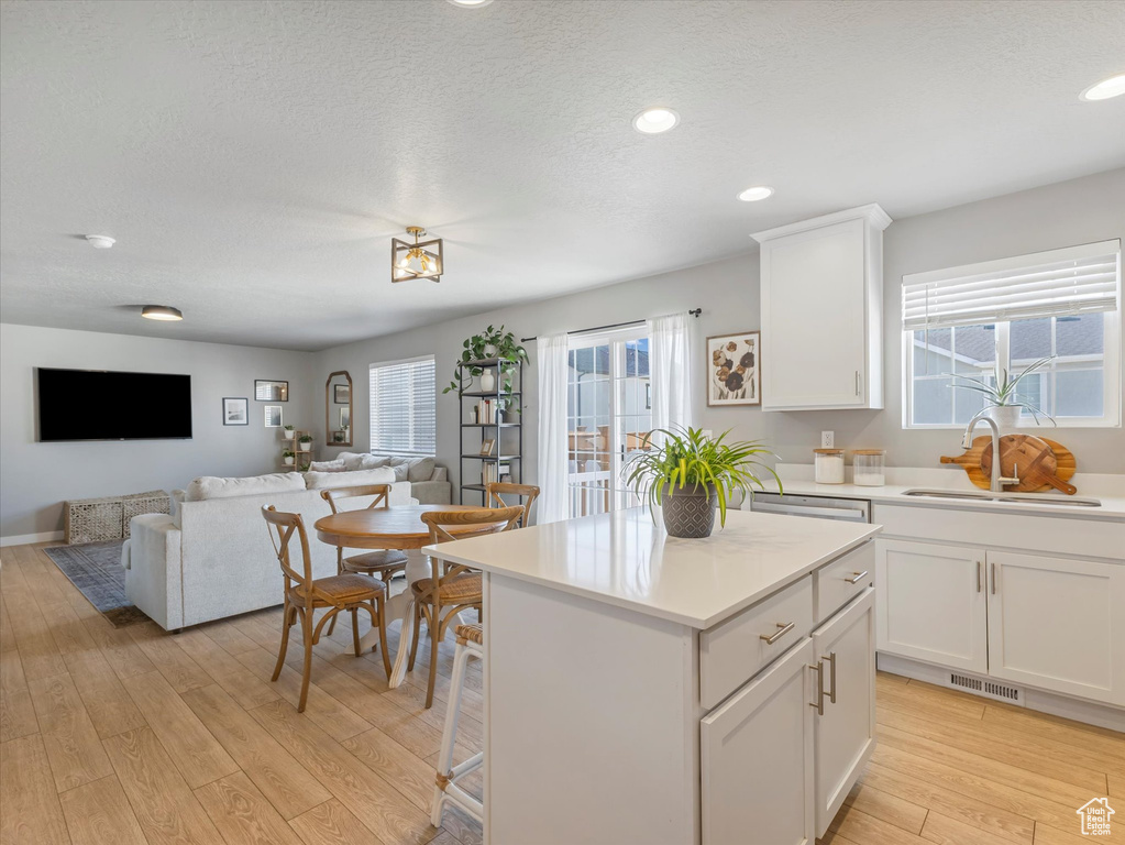 Kitchen featuring light wood finished floors, healthy amount of natural light, light countertops, white cabinets, and recessed lighting