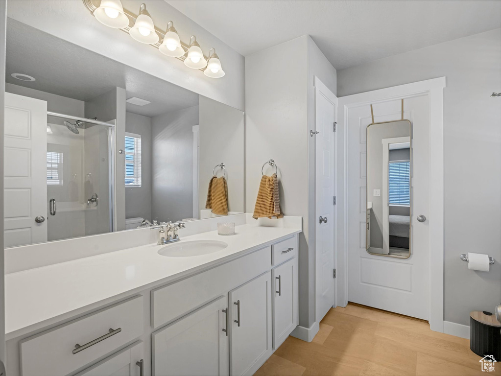 Ensuite bathroom with vanity, a stall shower, and wood finished floors