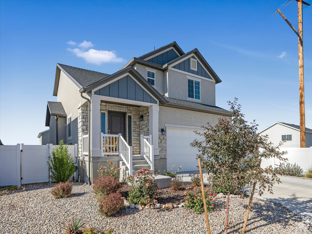View of front of house featuring stone siding, an attached garage, concrete driveway, board and batten siding, and roof with shingles