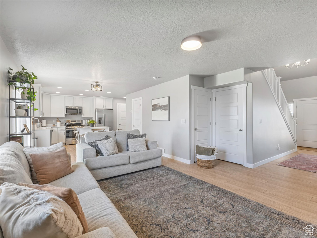 Living area featuring a textured ceiling, light wood-style flooring, and recessed lighting