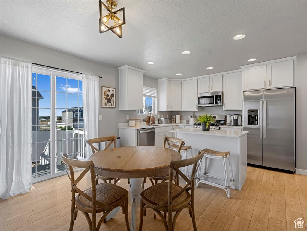 Dining area with light wood-style flooring, plenty of natural light, recessed lighting, and a textured ceiling
