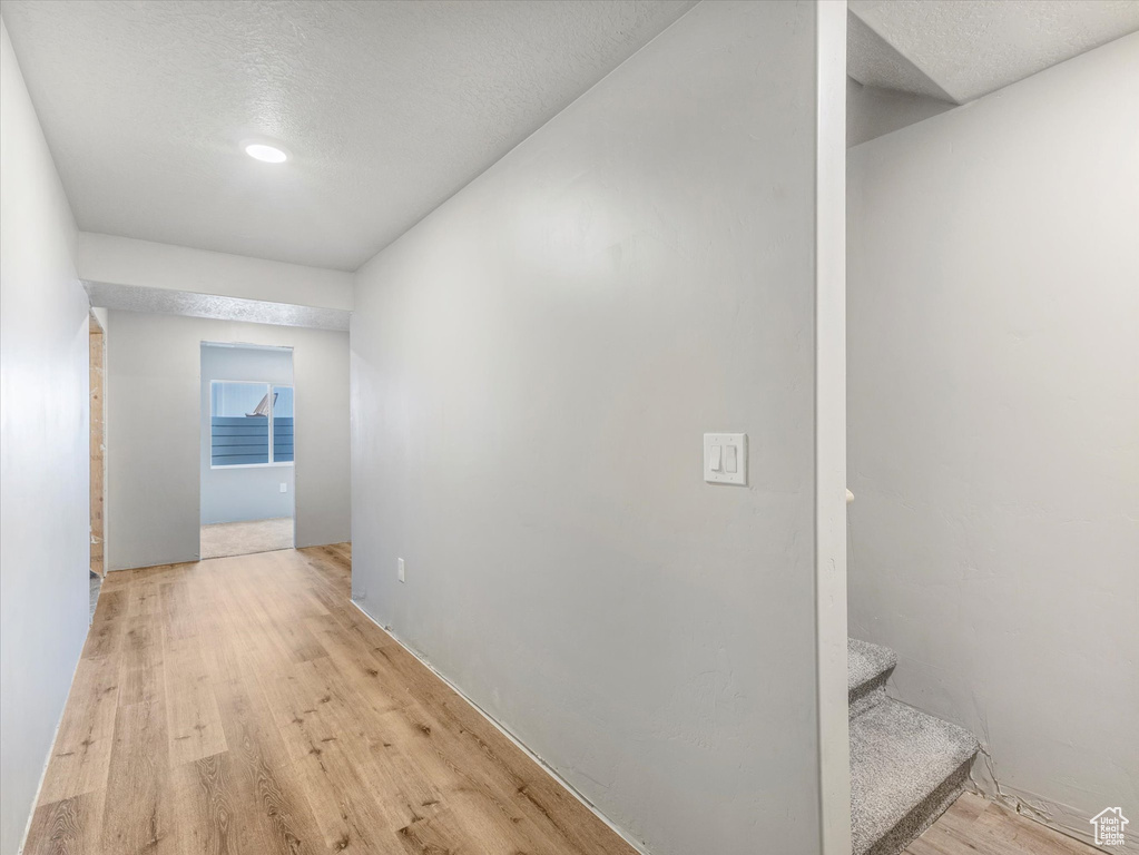 Hall featuring light wood-style floors, stairway, and a textured ceiling