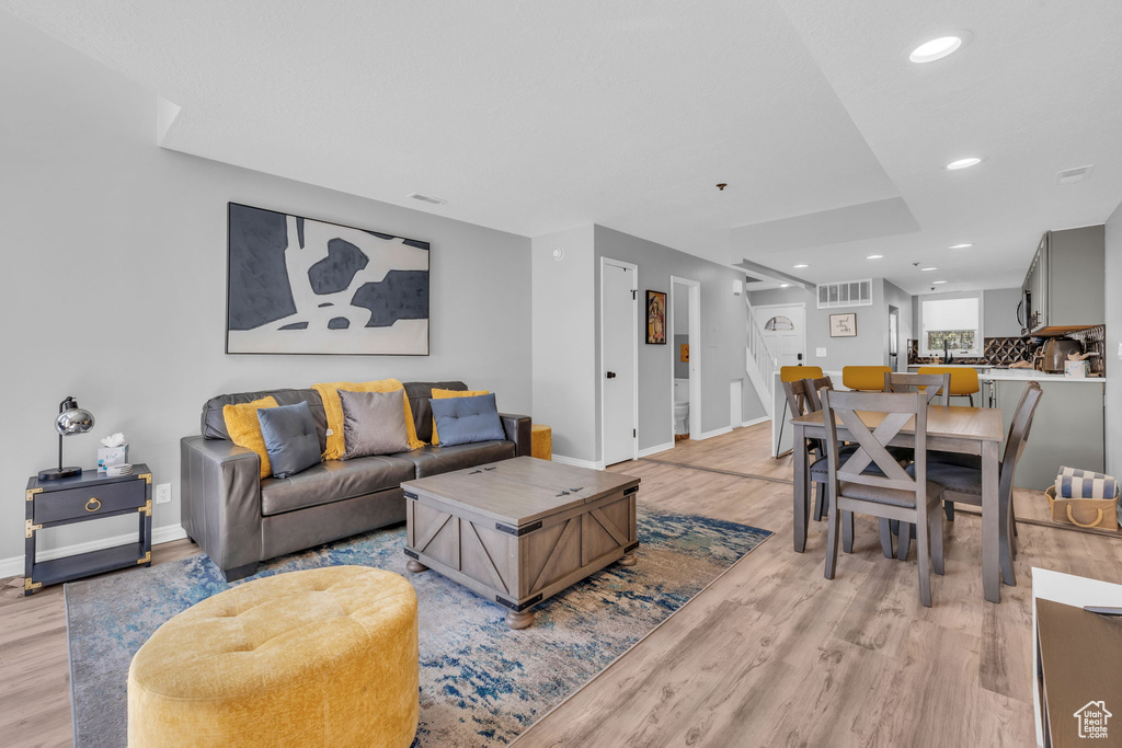 Living room with light wood-style floors, recessed lighting, and stairs