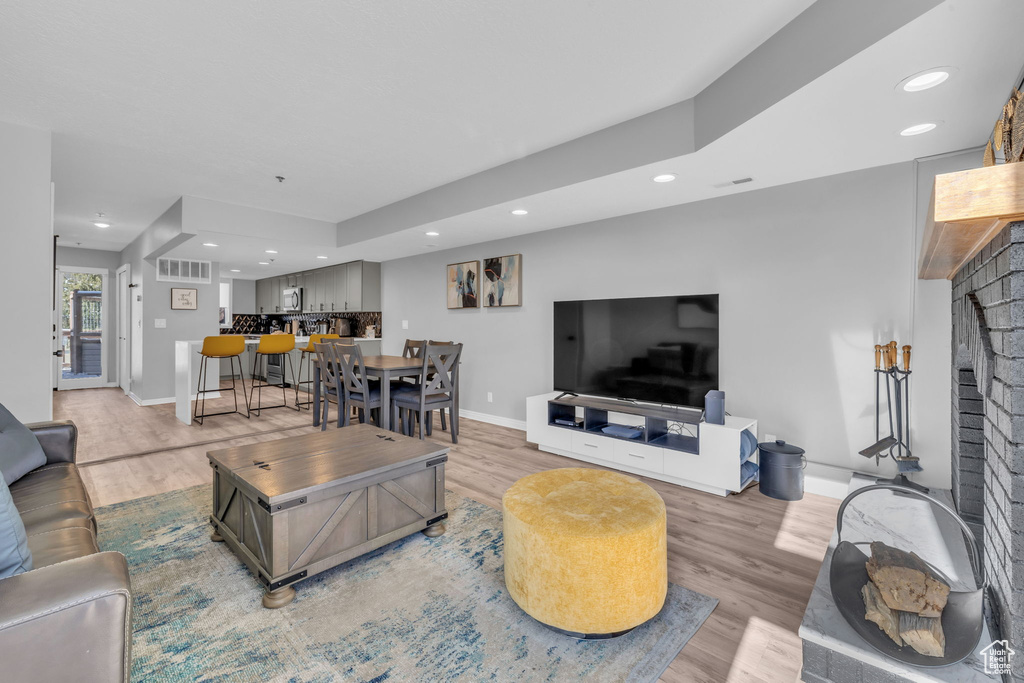 Living room with a brick fireplace, recessed lighting, and light wood-type flooring