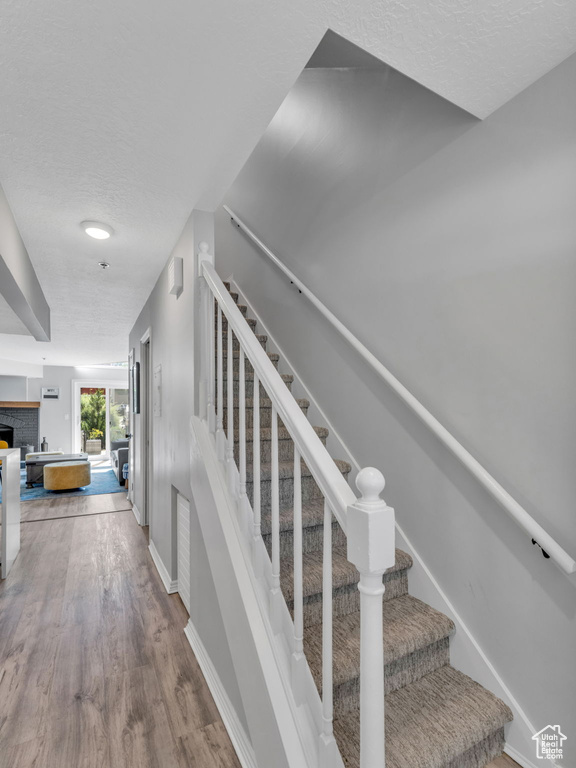 Stairway with wood finished floors, a fireplace, and a textured ceiling