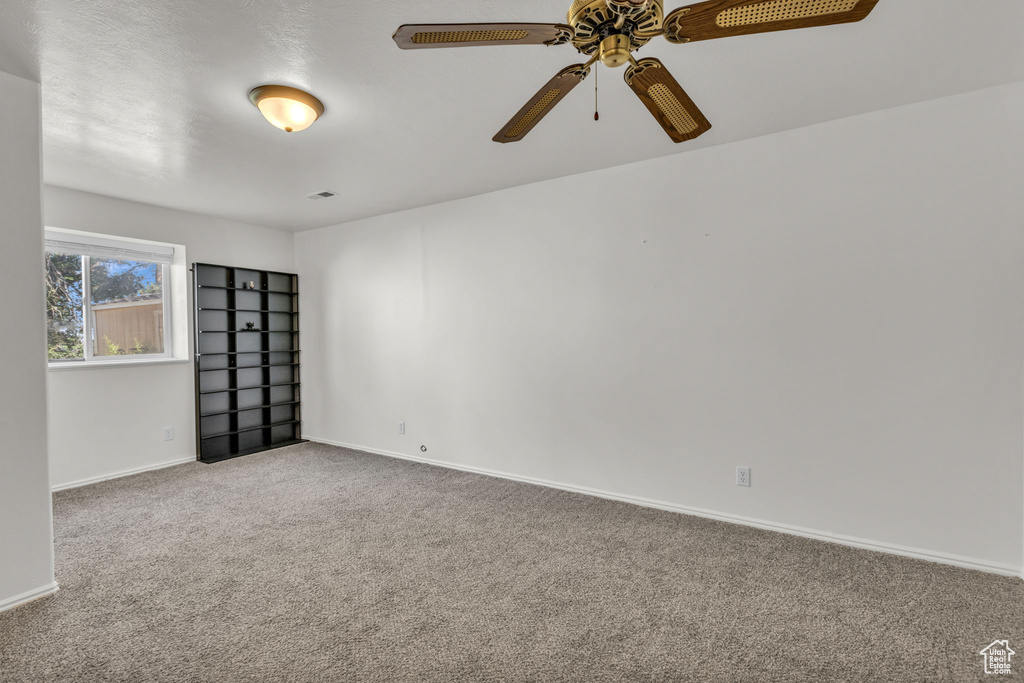 Carpeted spare room with baseboards and ceiling fan