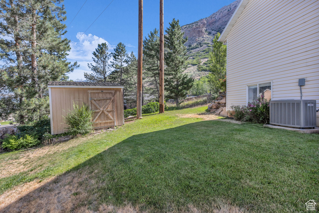 View of green lawn featuring a shed and a mountain view