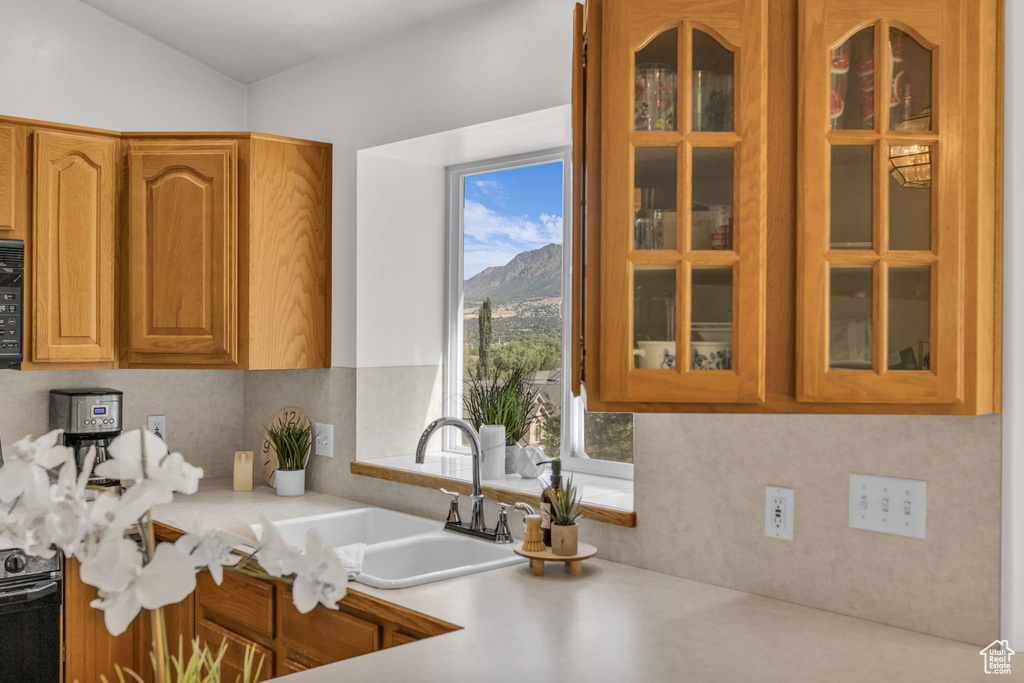 Kitchen featuring light countertops, glass insert cabinets, a mountain view, and brown cabinetry