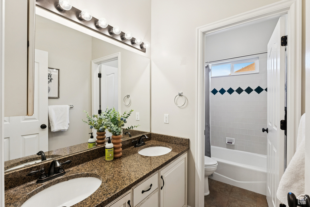Full bathroom featuring double vanity, shower / bath combo, and tile patterned flooring