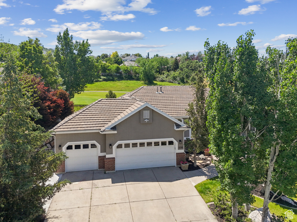 View of front of home with brick siding, stucco siding, concrete driveway, an attached garage, and a tiled roof