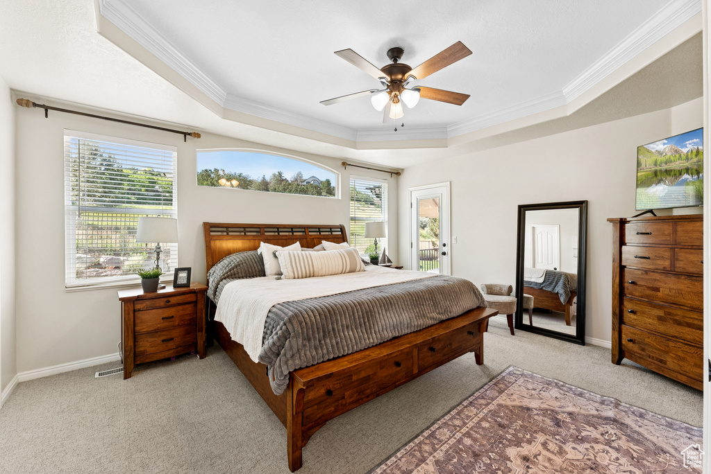 Bedroom featuring a tray ceiling, crown molding, light colored carpet, access to outside, and ceiling fan