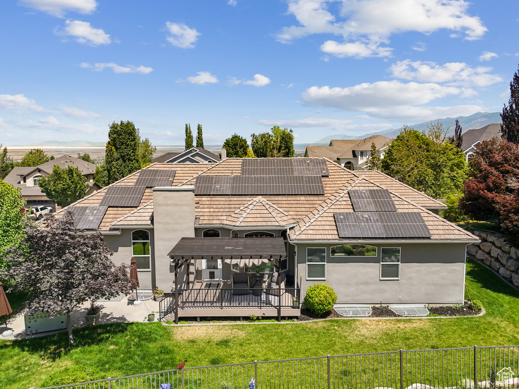 Rear view of house with a fenced backyard, stucco siding, solar panels, a wooden deck, and a tile roof
