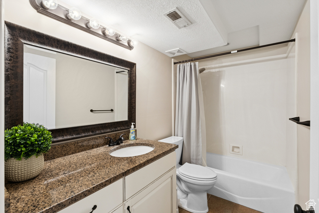 Full bathroom featuring vanity, shower / tub combo, a textured ceiling, and tile patterned floors