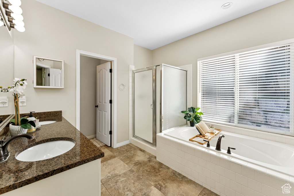 Bathroom with double vanity, a bath, and a stall shower