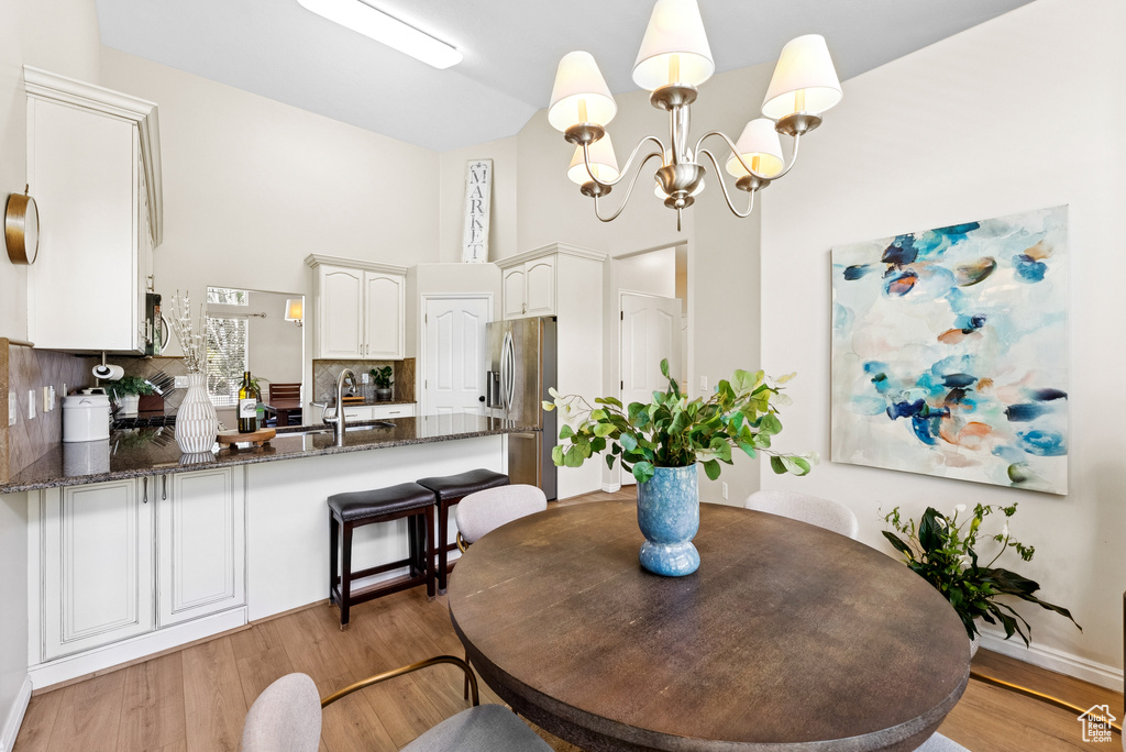 Dining space with a chandelier, light wood-type flooring, and high vaulted ceiling