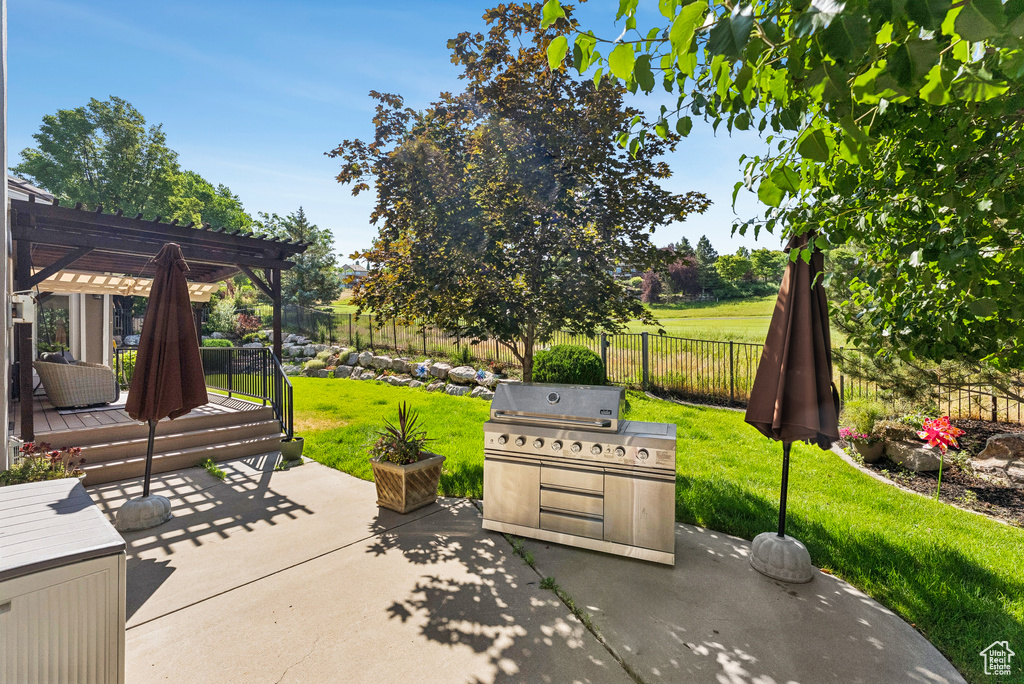 Fenced backyard featuring a pergola, a grill, a patio, and a deck