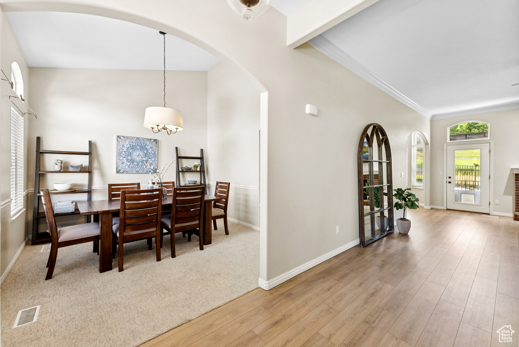 Dining space featuring arched walkways, wood finished floors, a chandelier, and crown molding