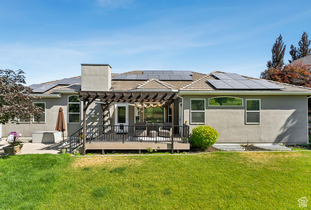 Rear view of property featuring a pergola, stucco siding, and a lawn