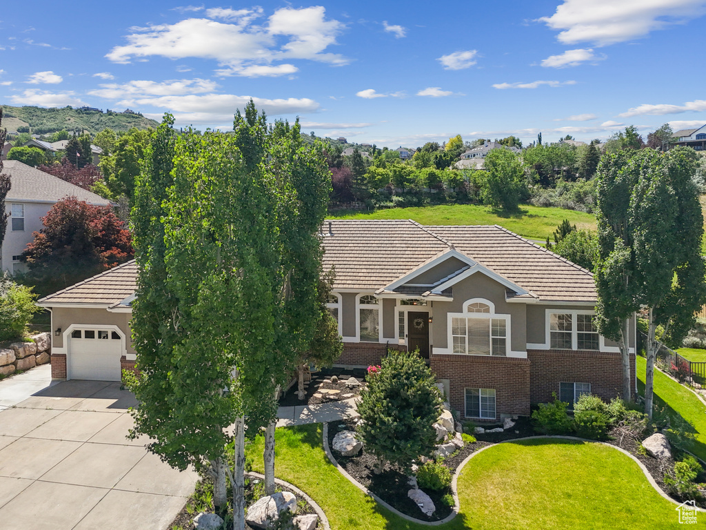 Ranch-style home with brick siding, driveway, a garage, and a tiled roof