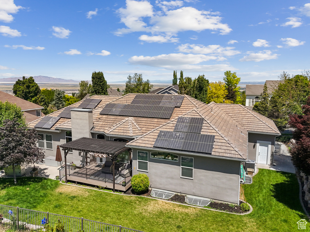 Back of property with solar panels, stucco siding, a deck, and a tiled roof