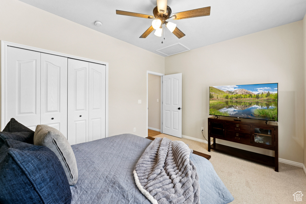 Bedroom with light colored carpet, a closet, and ceiling fan