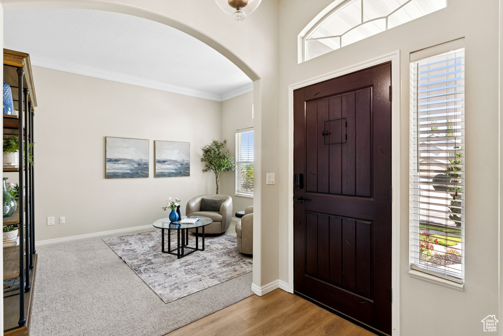 Entrance foyer featuring arched walkways, crown molding, healthy amount of natural light, and wood finished floors