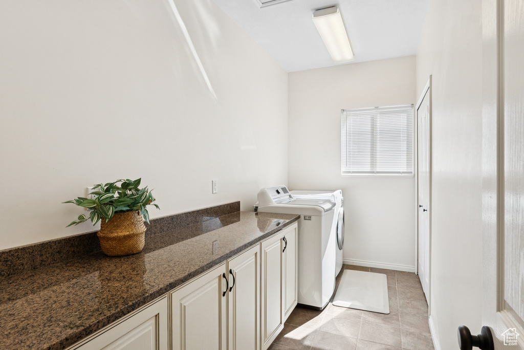 Washroom featuring washer and dryer, light tile patterned floors, and cabinet space