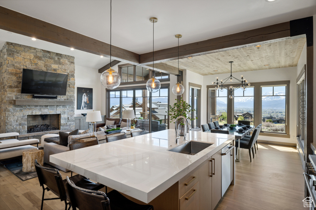 Kitchen featuring wood finished floors, healthy amount of natural light, beamed ceiling, an island with sink, and open floor plan