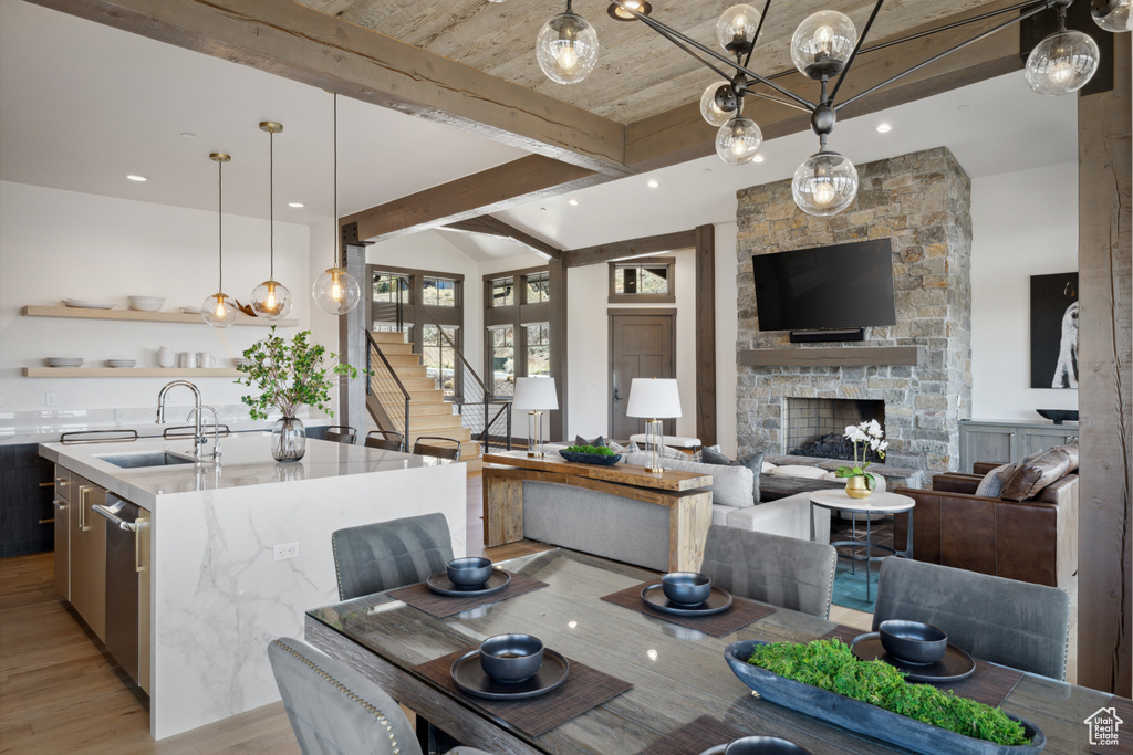 Dining room featuring light wood-style floors, stairs, a fireplace, beam ceiling, and recessed lighting
