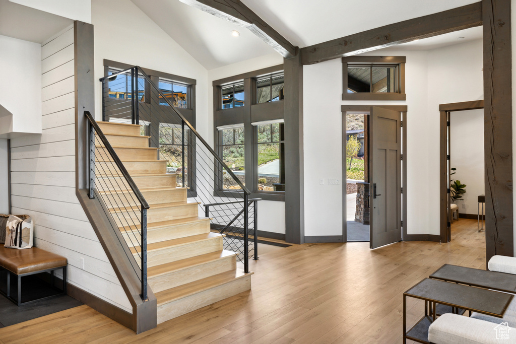 Entrance foyer with high vaulted ceiling, stairway, hardwood / wood-style floors, and beam ceiling