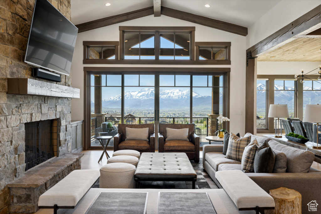 Living room with beam ceiling, a mountain view, a stone fireplace, wood finished floors, and a chandelier