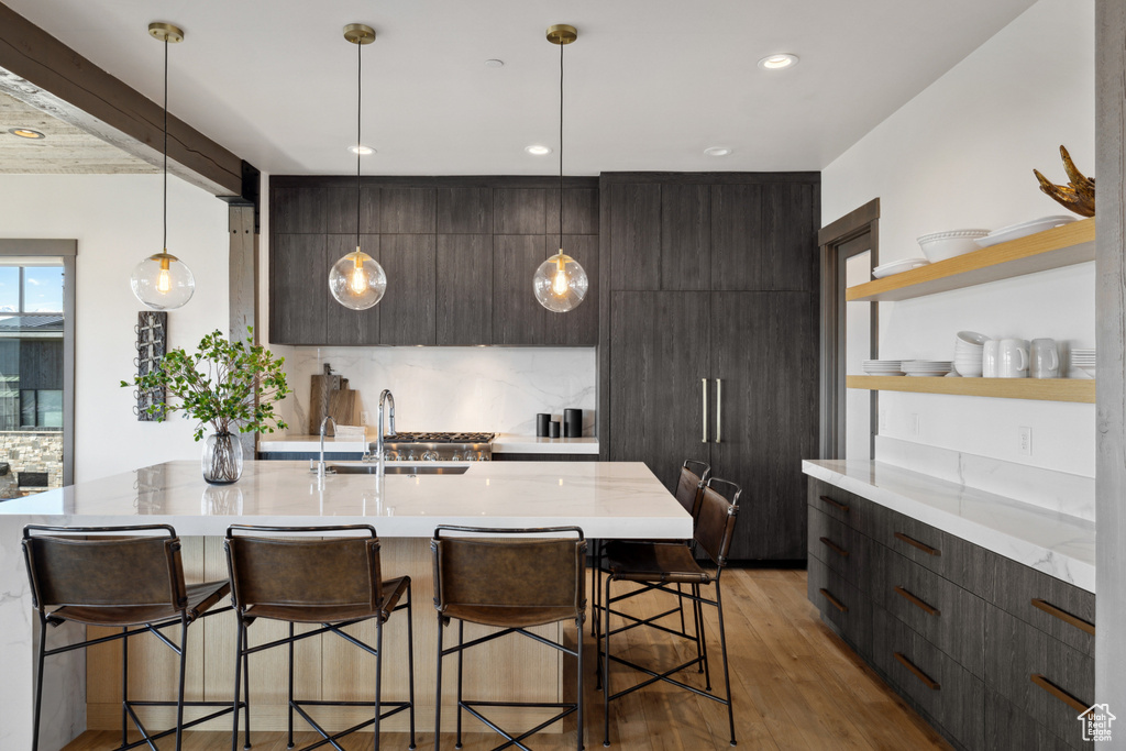 Kitchen featuring modern cabinets, open shelves, light wood-style floors, a kitchen bar, and recessed lighting