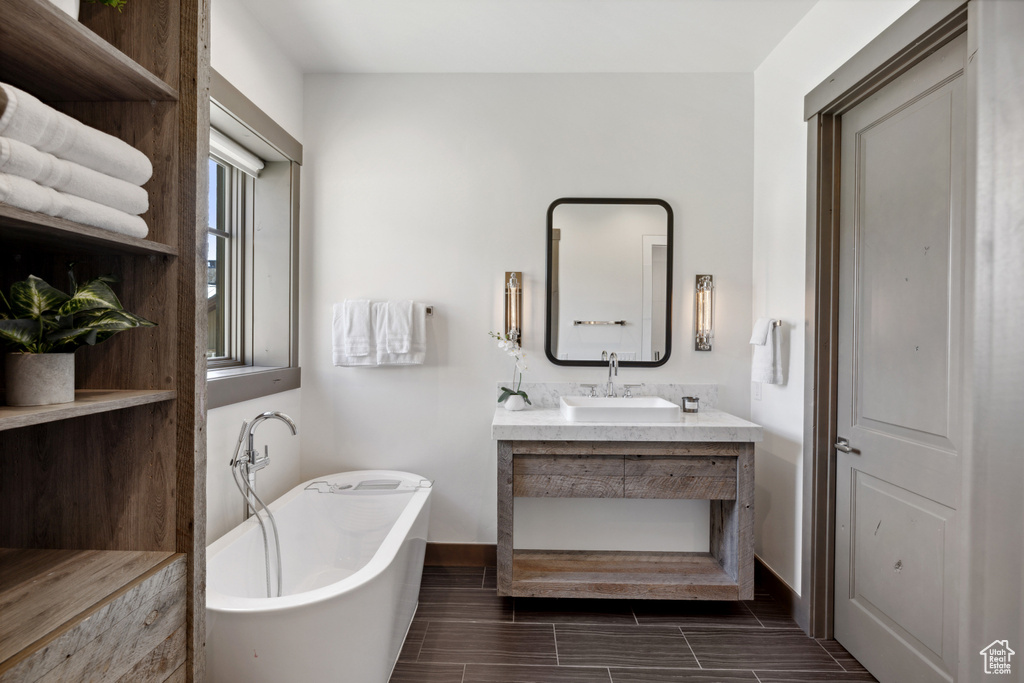 Full bathroom featuring a freestanding tub, vanity, and wood finish floors