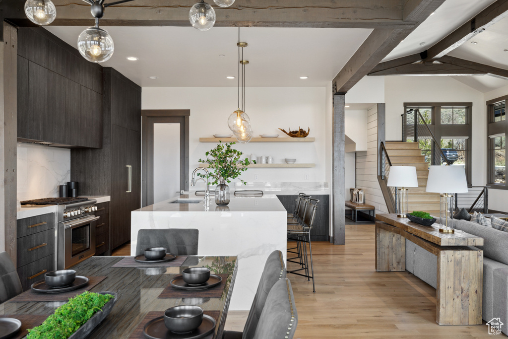 Kitchen featuring stainless steel range, light wood-type flooring, light countertops, open shelves, and recessed lighting