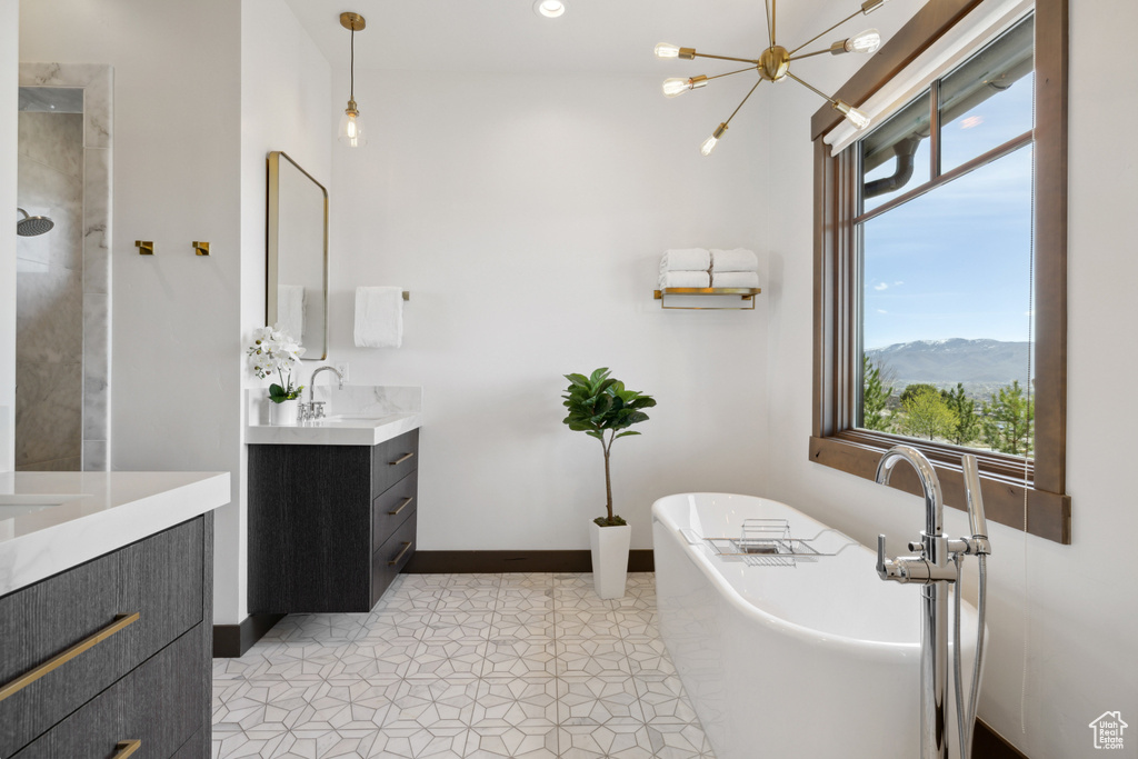 Full bath featuring vanity, a soaking tub, and a chandelier