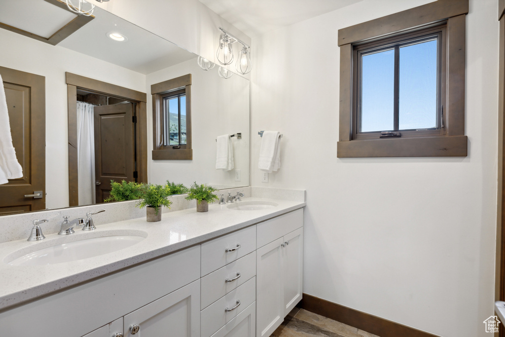 Full bathroom featuring double vanity, plenty of natural light, and recessed lighting