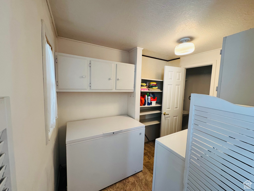 Laundry area featuring washing machine and clothes dryer, cabinet space, and a textured ceiling