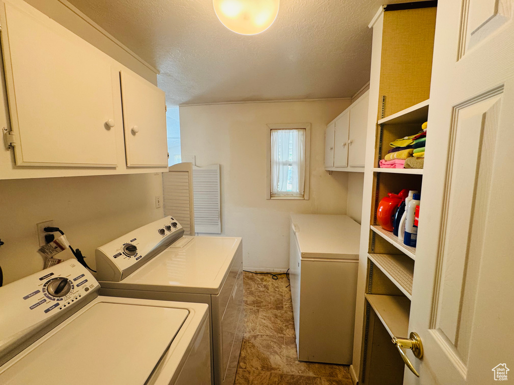 Laundry room featuring cabinet space, separate washer and dryer, and a textured ceiling
